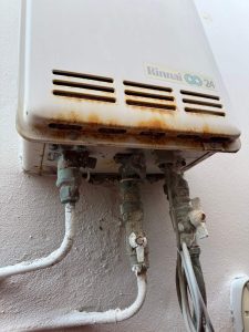 Old and rusted Rinnai Infinity gas hot water system before replacement at a North Bondi home.